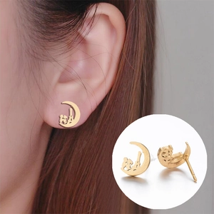 Detail view of golden crescent moon earrings with cat silhouette on model and close-up