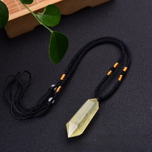 Macro detail of a natural citrine hexagonal prism pendant with a black woven cord