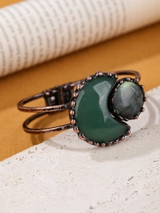 Macro shot of bronze bangle with moon-shaped green gemstone and round labradorite inlay