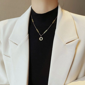 Detail view of gold-plated titanium steel necklace on a model wearing professional attire