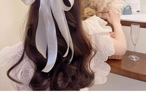 Elegant oversized white sheer ribbon bow hair clip with a pearlescent finish on long hair