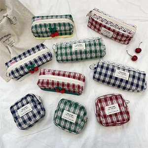 Macro detail of plaid fabric pouches with cherry decor and lace on white cloth