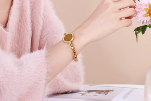 Close-up of gold coin pendant bracelet with sparkling crystals on a woman's wrist