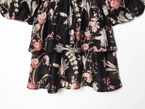 Detail of floral print layered ruffle dress showing woven texture and black tiered hem