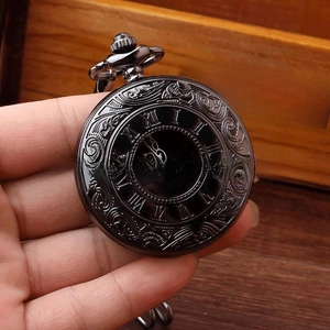 Detail of vintage black pocket watch with embossed floral texture and Roman numerals