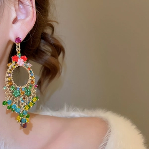 Detailed view of colorful crystal flower tassel earrings worn by a model in warm light