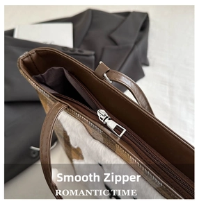 Detailed macro view of the smooth metal zipper and brown faux fur texture on tote bag