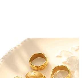 Detailed macro view of gold quilted pattern rings displayed on a stylish ceramic plate