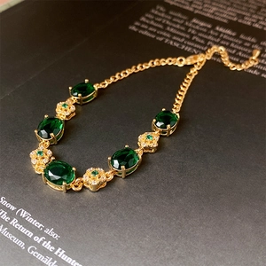 Close-up of emerald floral bracelet with gold plating and crystals on art book