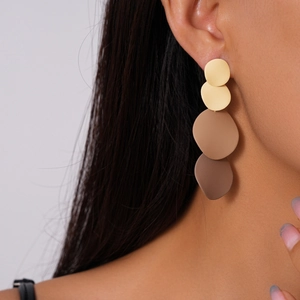 Close-up of matte geometric drop earrings with yellow to dark brown gradient circles