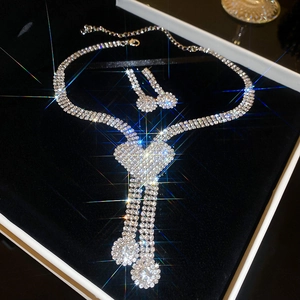 Detailed view of silver crystal heart necklace and tassel earrings in a jewelry box