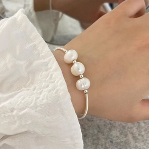 Detail of three freshwater pearls on a delicate silver-plated chain bracelet worn on wrist