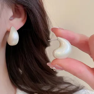 Elegant aurora white teardrop acrylic earrings with silver posts shown on a model and hand