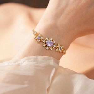 Detail of vintage gold bracelet with oval purple gemstone and zircon flower accents