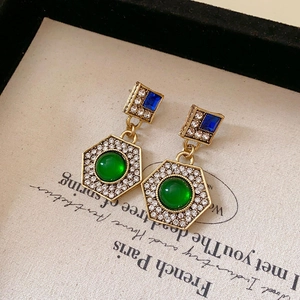 Detail of vintage gold earrings with blue crystals and a green cabochon gemstone