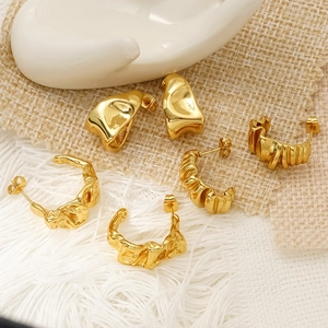 Three pairs of irregular gold pleated stainless steel hoop earrings on a ceramic hand display