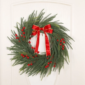 Detailed view of Christmas pine wreath with red berries and golden-edge bow decoration