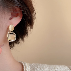 Gros plan détaillé de boucles d'oreilles dorées avec pierres œil-de-chat et strass