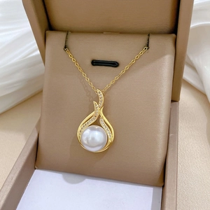 Macro detail of gold fish-tail necklace featuring a large pearl and sparkling pavé crystals