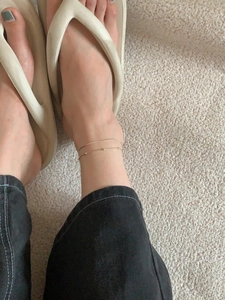 Detailed view of double-layer gold snake chain anklet worn on model's ankle with bead detail
