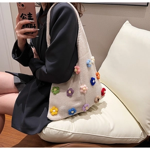 Mirror selfie showing the colorful crochet flower details on a beige knit tote bag