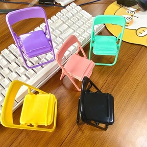 Mini macaron folding chair phone holders in various colors on a wooden desktop