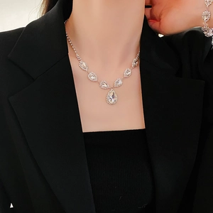 Détail du collier goutte d'eau argenté avec cristaux scintillants sur costume noir