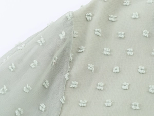 Détails du tissu en mousseline vert clair avec broderie en relief et texture