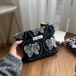 Detail shot of white butterfly embroidery on a black cotton canvas cosmetic bag