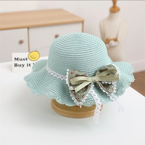 Detail of mint green straw hat with white lace trim and floral bow for girls