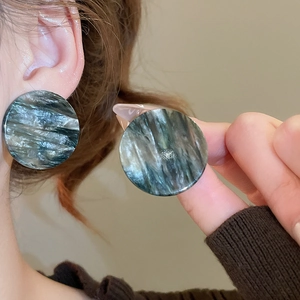 Gros plan de grandes boucles d'oreilles en acrylique avec texture marbrée foncée