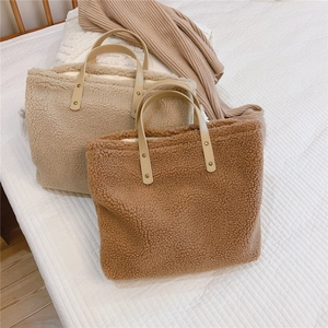 Close-up of fluffy beige and brown sherpa tote bags with leather handles on a white bed