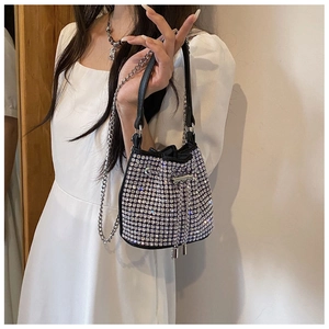 Silver rhinestone bucket bag with drawstring and chain strap shown on model shoulder