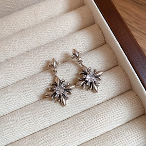 Detail of vintage silver cross earrings with iris motif and white zircon inlay