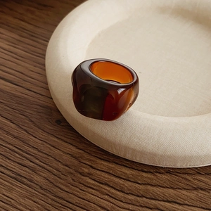 Close-up of translucent amber resin ring on a round fabric tray over a wooden table