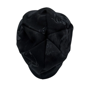Detailed top view of black knit beanie featuring gothic jacquard patterns and star stitching