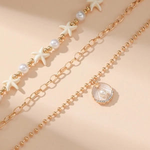 Detail of gold starfish pearl anklet set with seashell pendant and sparkling rhinestones
