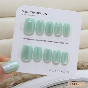 Mint green cat eye press-on nails set with glossy pearlescent finish on display card