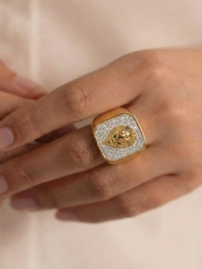 Close-up of gold lion head ring with green stone eyes and micro-paved crystals
