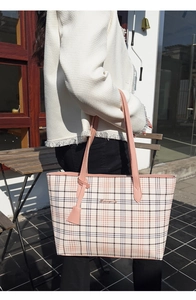 Macro detail of the metal logo and pink checkered pattern on a large tote bag
