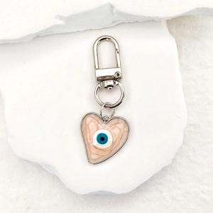 Close-up of heart-shaped evil eye keychain with pink quicksand texture and silver clip