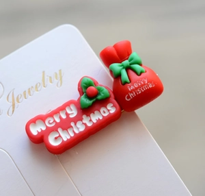 Macro detail of red Merry Christmas hair clips with holly and gift bag design