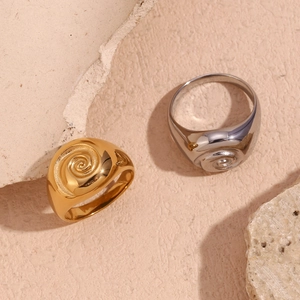Detail of 18K gold and silver plated rings with spiral texture on natural stone surface