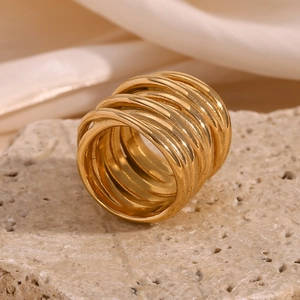 Detail shot of multi-layer spiral gold ring on stone texture background with silk fabric