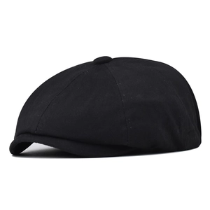 Detail of classic black cotton newsboy cap featuring eight-panel crown and top button