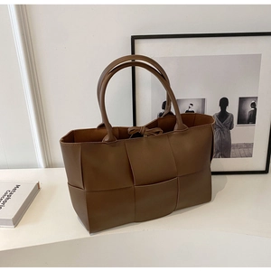 Detailed view of brown woven tote bag with premium leather texture and drawstring interior