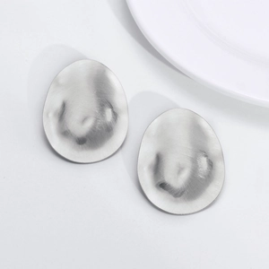 Macro shot of silver irregular oval stud earrings with brushed hammered metal texture