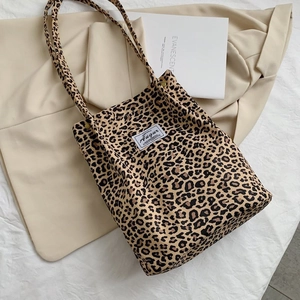 Detailed macro view of leopard print canvas tote bag with woven brand label and shoulder straps