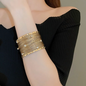 Exaggerated layered gold metal cuff bracelet with rhinestones on model with black outfit