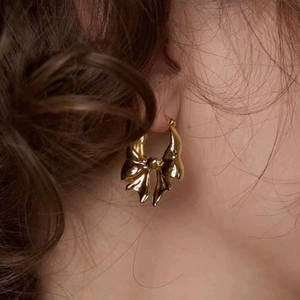 Elegant 18K gold plated brass bow knot hoop earrings on model with high gloss finish